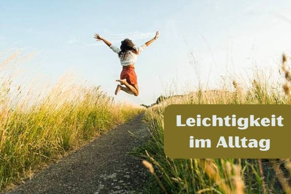 Eine Frau springt voller Freude und mit Leichtigkeit auf einem schmalen Weg in die Luft