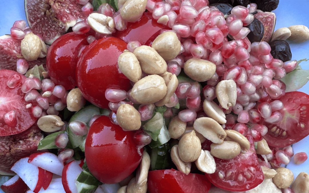 Teller mit leckerem Salat mit Feigen, Tomaten, Granatapfel, Oliven und Erdnüsse