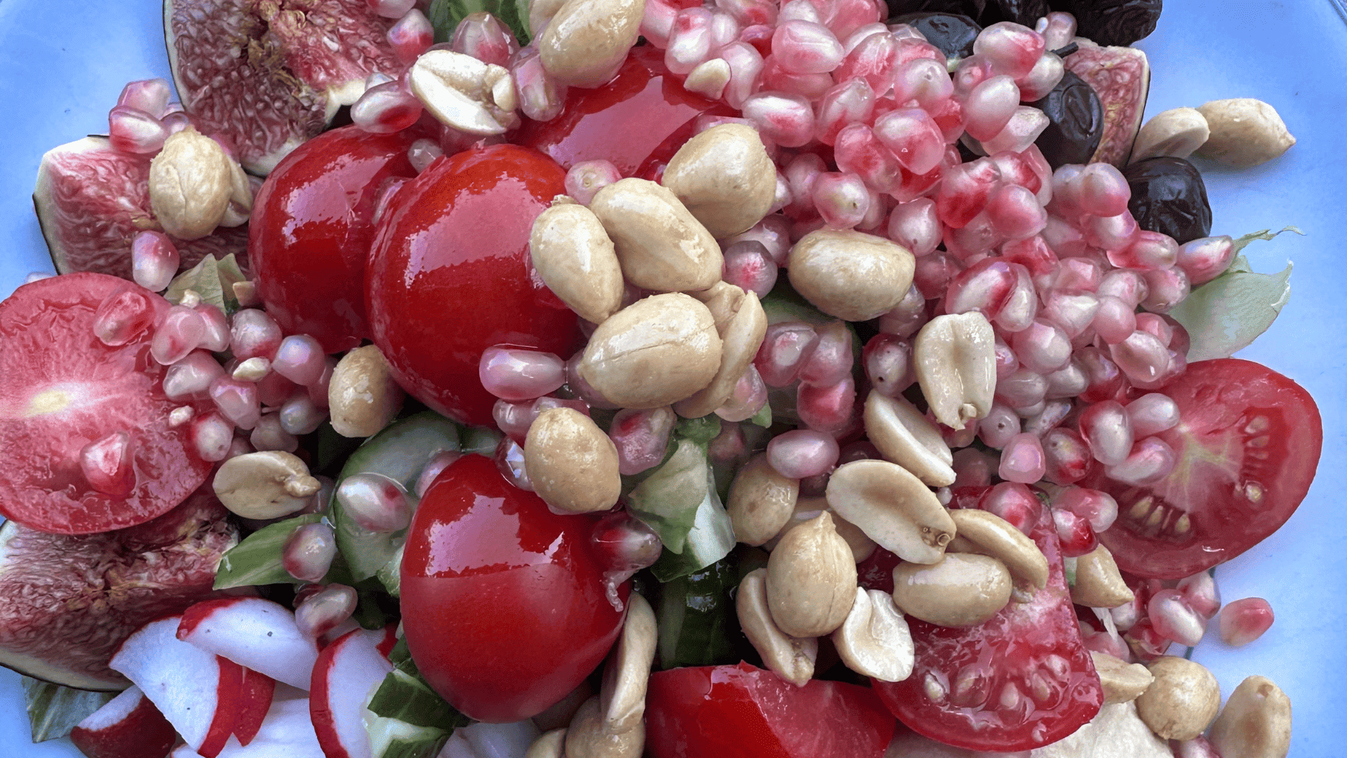 Teller mit leckerem Salat mit Feigen, Tomaten, Granatapfel, Oliven und Erdnüsse