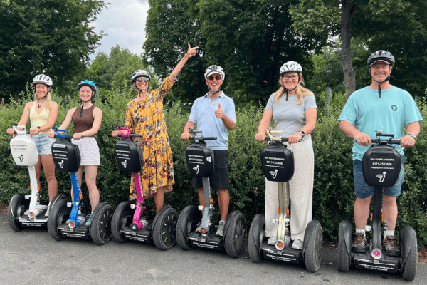 6 Personen stehen für ein Foto nebeneinander mit ihrem Segway